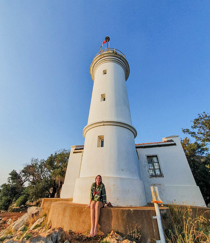 A hiker smiling in front of Gelidonya lighthouse, a landmark on the Lycian Way trail. 