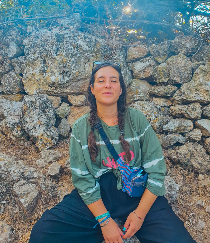 A photo of a Lycian Way hiker taking a break from the trek by sitting on mountain rocks. 