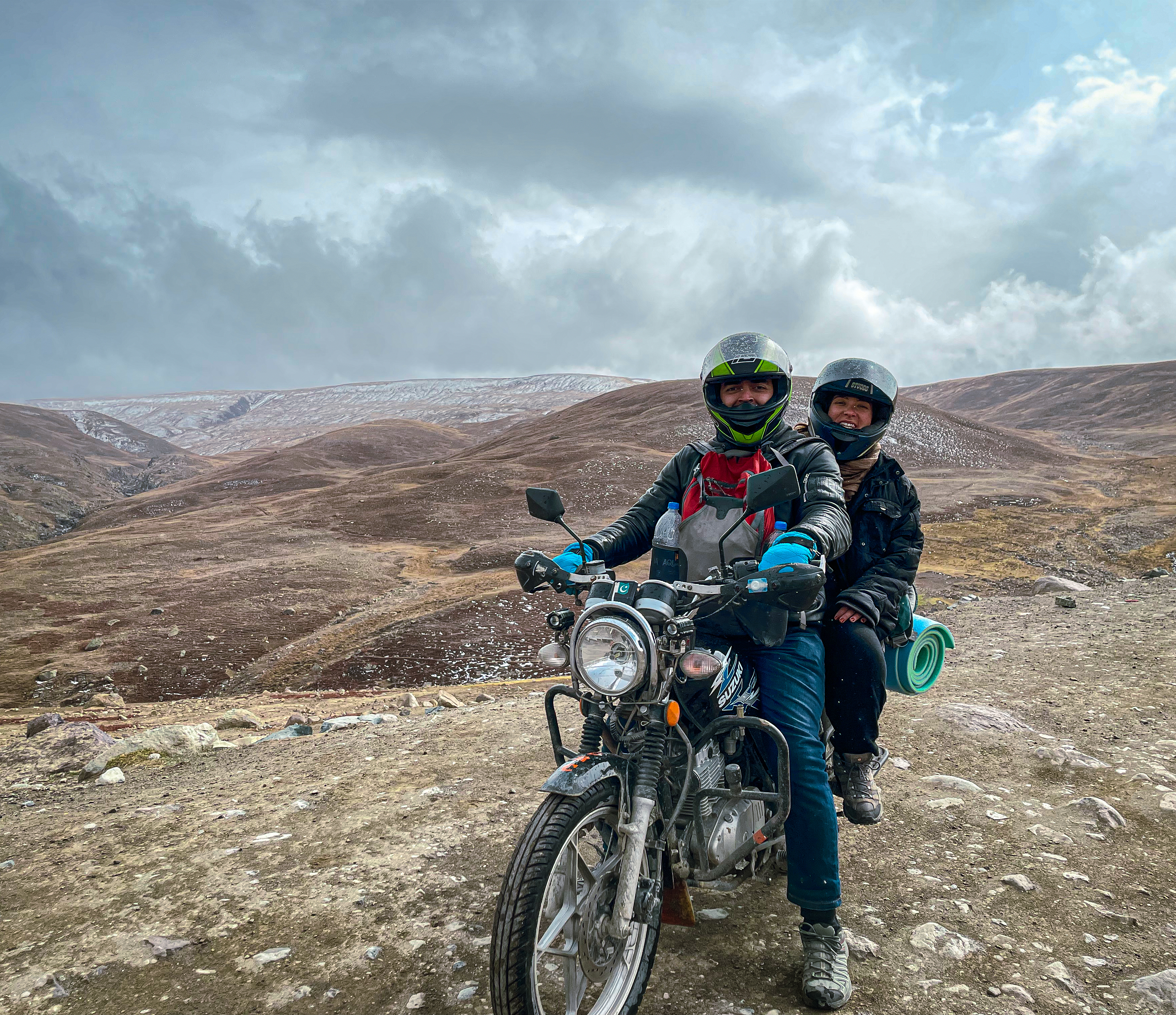 Two motorcycle riders smiling inside of Deosai National Park in Pakistan